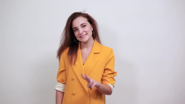 Cheerful young woman showing victory gesture in yellow jacket — Stock Video