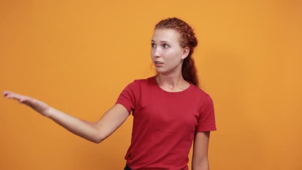 Söt ung kvinna i röd skjorta håller hand på munnen, ler — Stockvideo