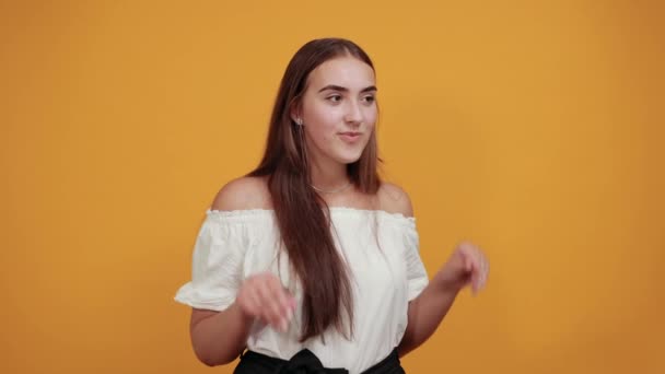 Mujer joven caucásica sonriendo, mostrando las palmas en la cámara con los ojos abiertos — Vídeo de stock