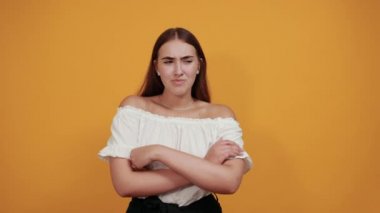 Hayal kırıklığına uğramış esmer kadın dudaklarını üflüyor, birine kırgın, ellerini çapraz yapıyor.