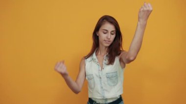 Mavi kot gömlekli neşeli beyaz kadın yumruklarını kaldırıyor, gülümsüyor.