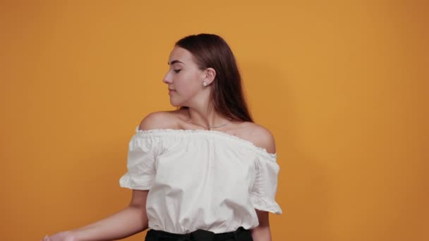 Mulher jovem encantadora forte mostrando músculos, sorrindo na parede laranja — Vídeo de Stock