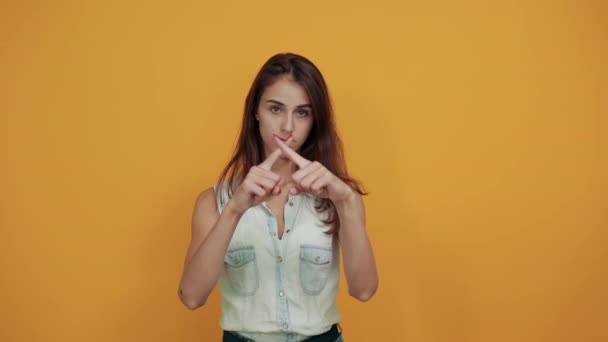 Jovem mulher de camisa jeans azul mantendo as mãos cruzadas, olhando diretamente — Vídeo de Stock