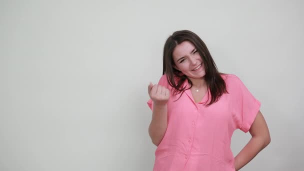 Brunette Kaukasische jonge vrouw in roze shirt houden vuisten op camera, glimlachen — Stockvideo