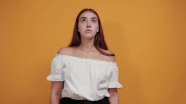 Korkmuş genç bir kadın işaret ediyor, korkmuş, şok olmuş görünüyor.