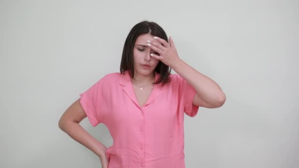 Barna fehér fiatal nő rózsaszín ingben felfelé mutat, zavarodottnak látszik — Stock videók