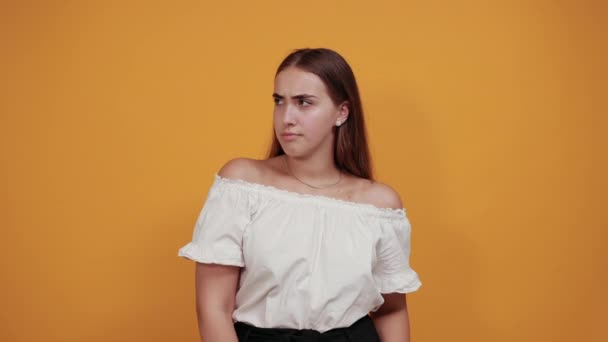 Jeune femme ennuyeuse fatiguée, regardant la caméra isolée sur un mur orange — Video