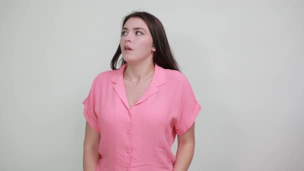 Розчарована жінка в рожевій сорочці тримає руки схрещеними вказуючими пальцями вбік — стокове відео