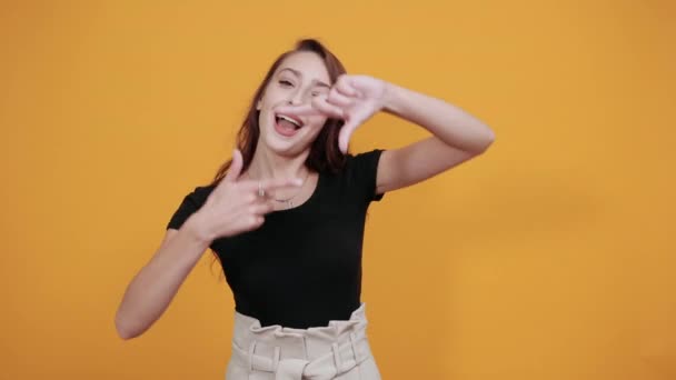 Vicces nő fekete ingben csinál keret gesztus a kamera, úgy néz ki, boldog — Stock videók