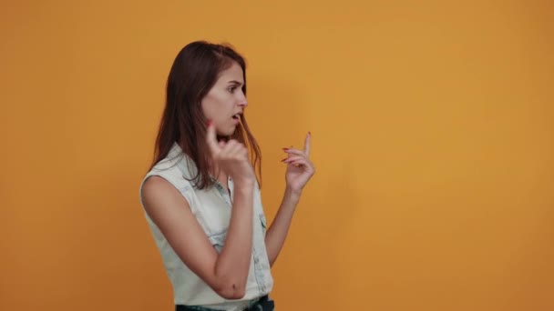 Angry caucasian young woman spreads hands isolated on orange wall — Stock Video