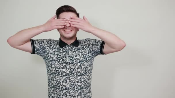 Portrét usměvavého mladého muže v neformální košili zakryté oči s rukama — Stock video