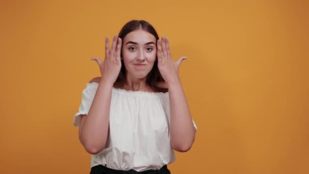 Mujer atractiva manteniendo las manos cerca de la cara, sonriendo, esperando momento especial — Vídeos de Stock