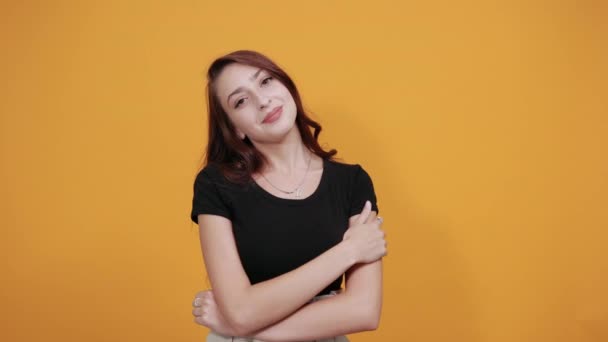 Atrakcyjna kobieta w czarnej koszuli trzymająca palec na policzkach, patrząca bezpośrednio — Wideo stockowe