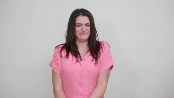 Teleurgesteld jonge vrouw in roze shirt houden duimen naar beneden, direct op zoek — Stockvideo
