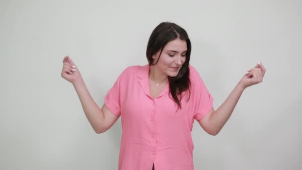 Vrolijke jonge vrouw houdt vuisten omhoog, glimlachend geïsoleerd op grijze muur — Stockvideo