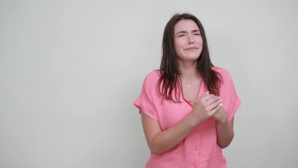 Aantrekkelijke jonge vrouw in roze shirt gesloten ogen. vuisten bij elkaar houden — Stockvideo