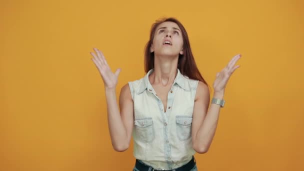Jonge vrouw in blauw denim shirt houdt handen omhoog, ziet er mooi uit — Stockvideo