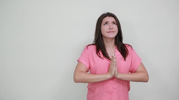 Pembe gömlekli, hayal kırıklığına uğramış beyaz kadın el ele tutuşup dua ediyor. — Stok video