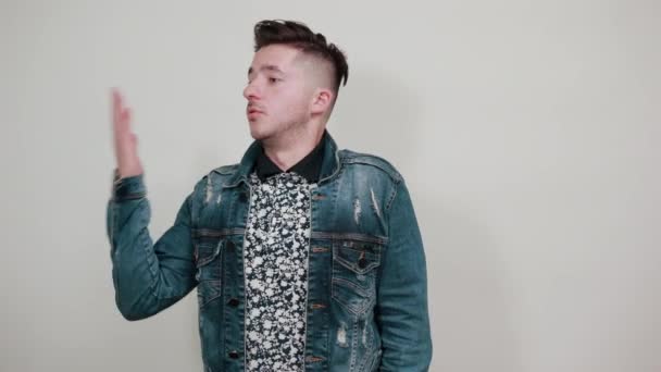 Jonge handsom man in mode shirt houden van handen en kijken opzij — Stockvideo