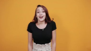 Çekici bir kadın, elini başının üstünde tutuyor, diğerini de cebinde tutuyor.