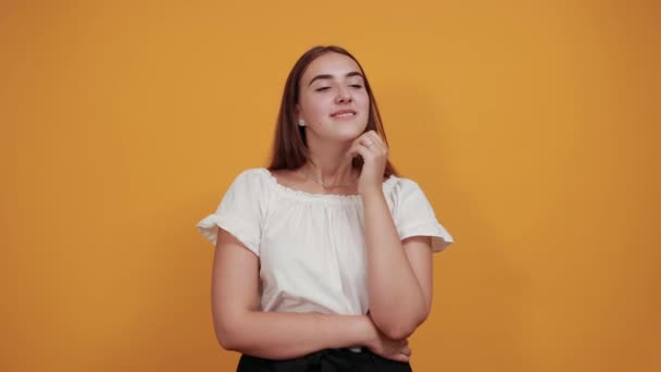 Vonzó kaukázusi fiatal nő fúj ajkak, küld levegő csók narancssárga fal — Stock videók