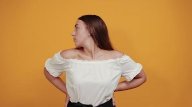 Çekici genç bir kadın ellerini arkada tutuyor, kızgın görünüyor.