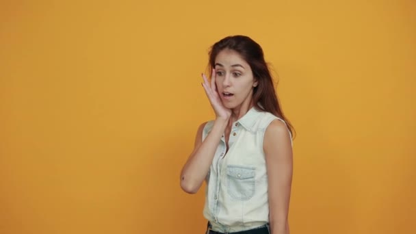 Blanke vrouw in blauw denim shirt houden hand in de buurt van de mond, op zoek geschokt — Stockvideo