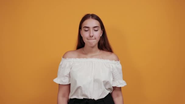 Atrakcyjna młoda kobieta wyciąga ręce, krzycząc odizolowana na pomarańczowej ścianie — Wideo stockowe