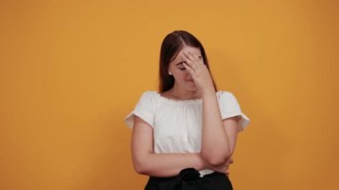 Sıkı bir kadın ellerini başının üstünde tutuyor, dalgalı saçlar, yukarı bakıyor, hayal kırıklığına uğruyor.