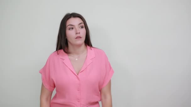 Aantrekkelijke dame in roze shirt houden hand op hoofd, op zoek moe, verward — Stockvideo