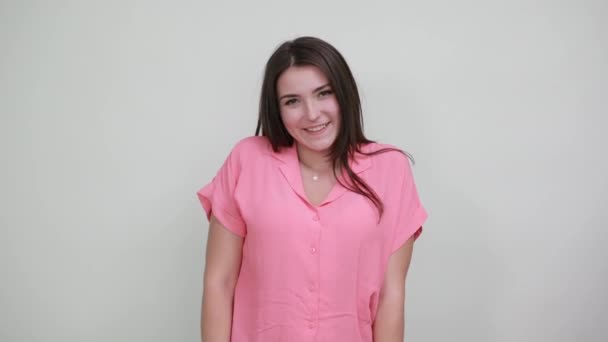 Mulher muito caucasiana jovem em camisa rosa fazendo forma de coração, olhando engraçado — Vídeo de Stock