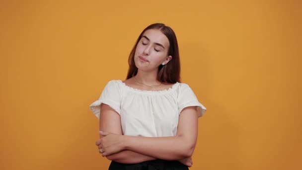 Resentful young woman blowing lips, keeping hands crossed on orange wall — Stock Video