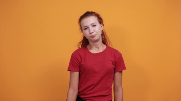 Mooie dame in rood shirt houdt vuisten omhoog, wijst direct, ziet er serieus uit — Stockvideo