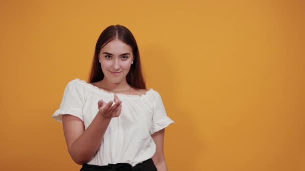 Aantrekkelijke jonge vrouw wijzend duimen naar zichzelf, glimlachend op oranje muur — Stockvideo