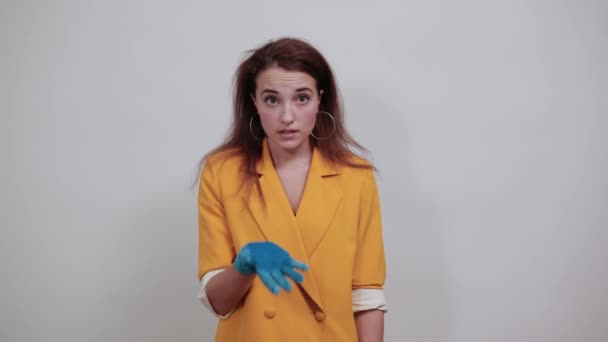Mujer joven y cansada con chaqueta amarilla, guantes azules con las manos en la cabeza — Vídeos de Stock