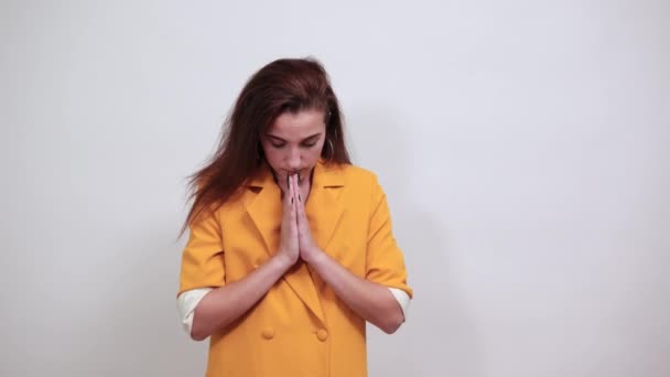Великолепная женщина в желтой куртке держит Ганса вместе, молится, смотрит вверх — стоковое видео