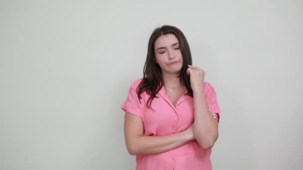 Atraktivní mladá žena drží jazyk za zuby, vypadá vážně na šedé stěně — Stock video