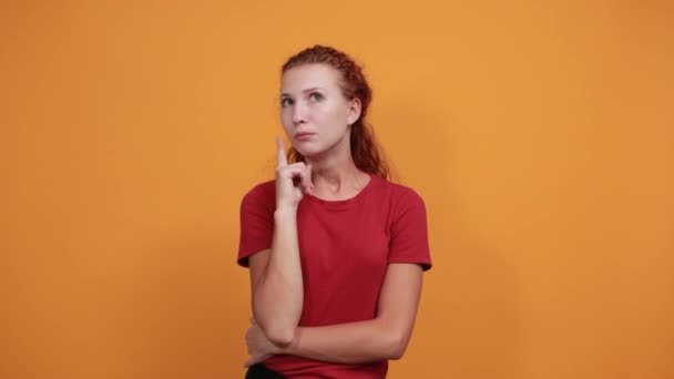 Saaie jonge vrouw in rood shirt houden hand op de wang, kijken teleurgesteld — Stockvideo