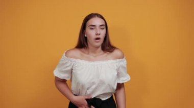 Çekici genç bir kadın ellerini karnına koyup karın ağrısı çekiyor.