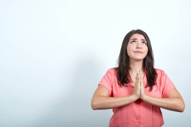 Pembe gömlekli barışçıl genç kadın el ele tutuşup dua ediyor.