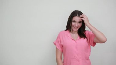 Katı bir genç kadın saçlarını tarıyor, saçlarını gri duvarda düzeltiyor.