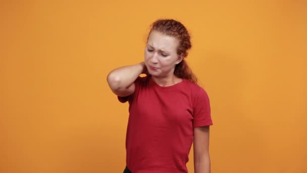 Mujer joven con camisa roja manteniendo la mano en el cuello, mueca dolorosa — Vídeos de Stock