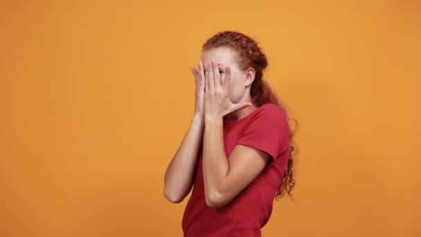 Chockad ung kvinna i röd skjorta täcker ansiktet med händer — Stockvideo