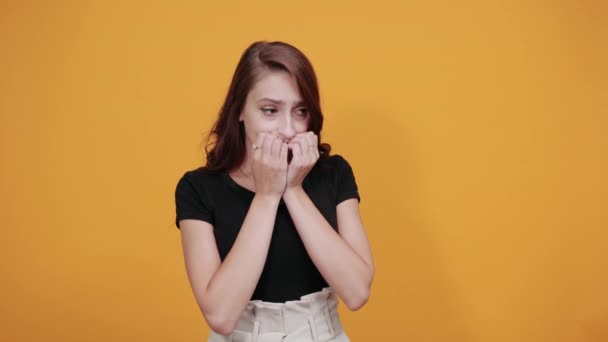 Rädd kvinna i svart skjorta håller nävarna på munnen, kramar sig själv — Stockvideo
