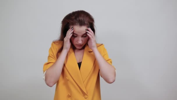 Mujer joven sorprendida en chaqueta amarilla manteniendo las manos en la cabeza con la boca abierta — Vídeos de Stock