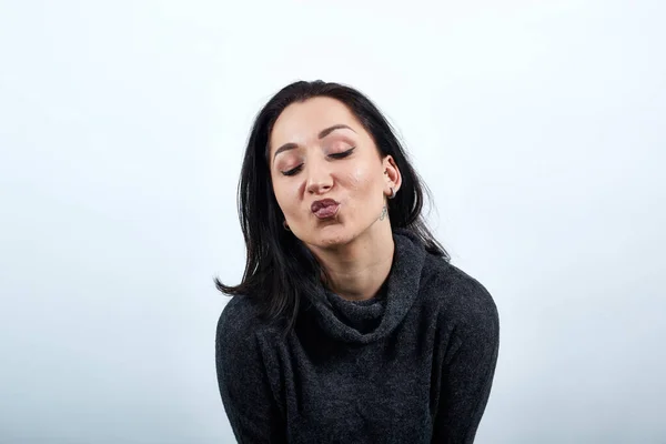 Charming woman in fashion black sweater keeping lips together, send air kiss