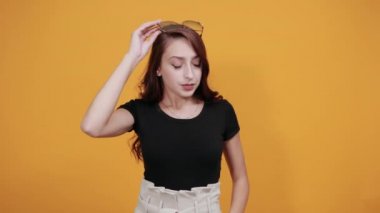 Yüzünde güneş gözlüğü olan, eli çenesinde olan genç bir bayan.