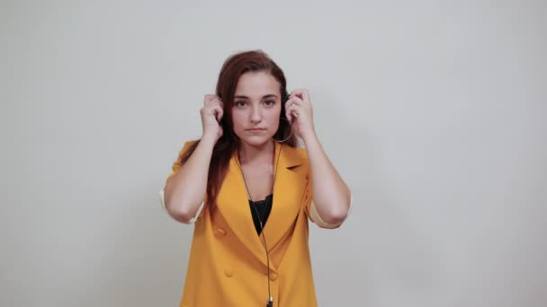 Mujer joven caucásica en chaqueta amarilla con auriculares, disfrutando de la música — Vídeo de stock