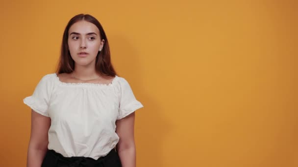 Cheerful young woman keeping hand on head, looking into distance, smiling — Stock Video