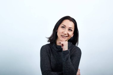 Çekici beyaz kadın. Elini çenesinde tutuyor, gülümsüyor..